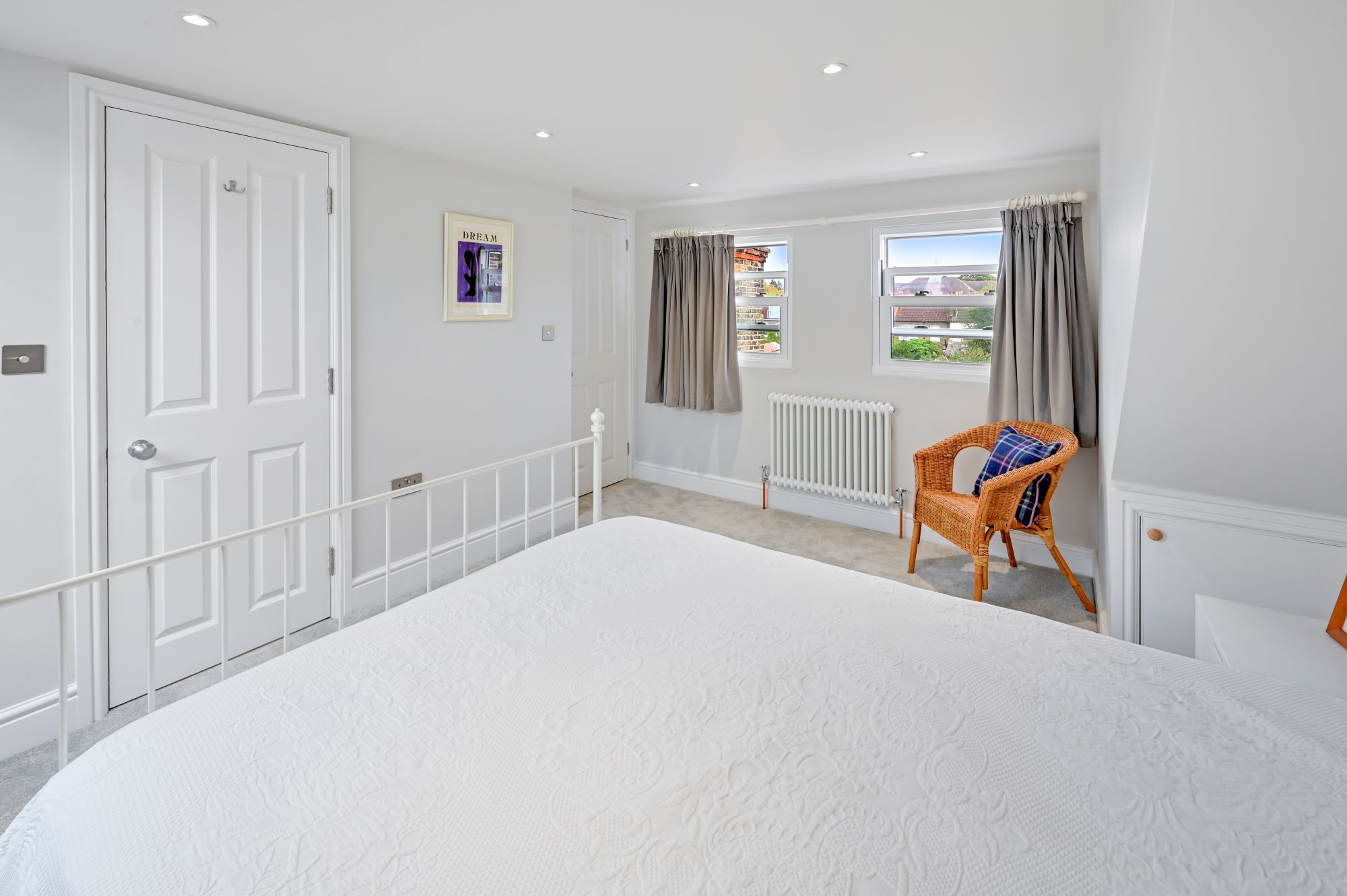 Finished loft bedroom with twin rear windows, recessed lighting, fitted storage and neutral finishes for the Wood Green N22 loft conversion page.