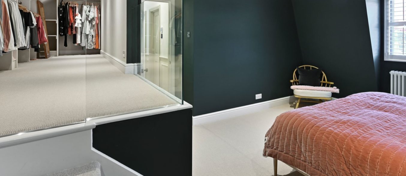 Spacious loft conversion bedroom with walk-in wardrobe, glass balustrade and staircase, featured on the Billericay CM12 Our Work page