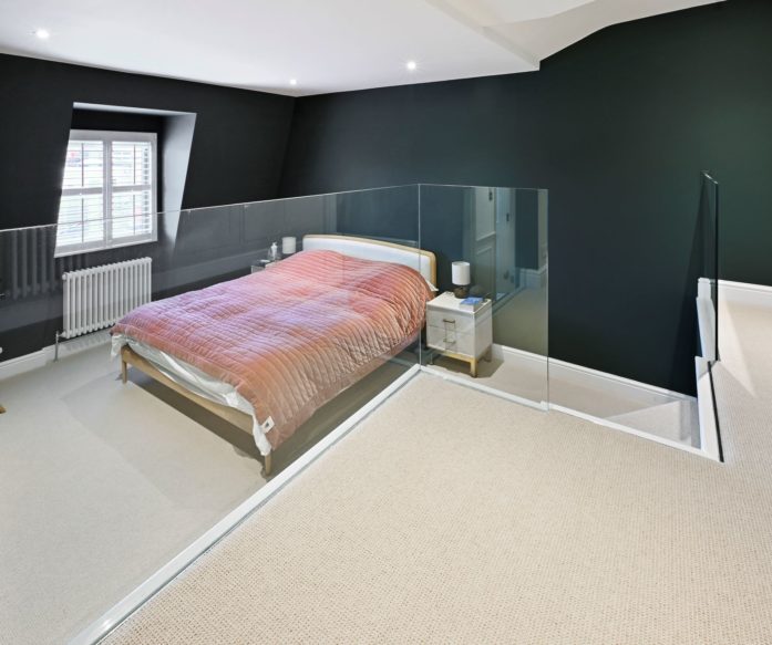 Finished loft conversion bedroom with dark feature walls, staircase and glass balustrade, featured on the Billericay CM12 loft conversion page