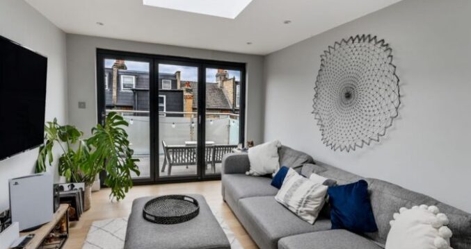 Modern loft living space with a roof dome, glazed doors and access to a balcony in Winchmore Hill N21