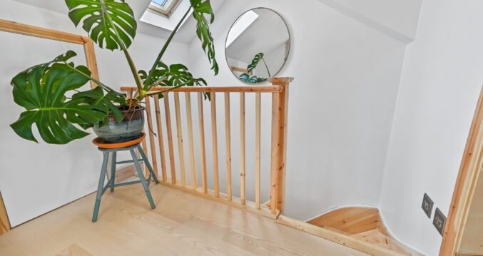 Bright loft staircase landing with timber balustrade, rooflight and natural wood flooring for the Wood Green N22 loft conversion page.
