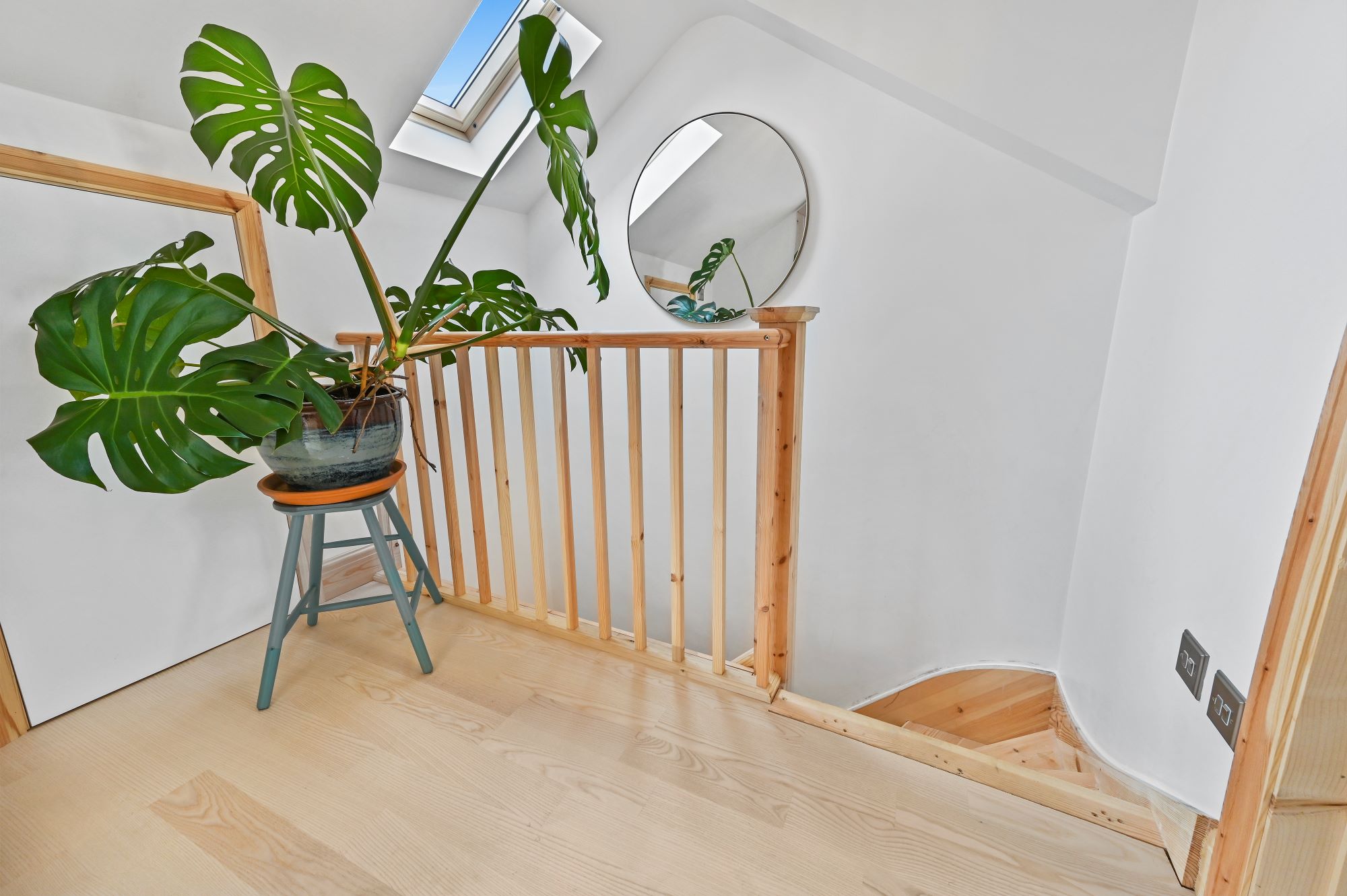 Bright loft staircase landing with timber balustrade, rooflight and natural wood flooring for the Wood Green N22 loft conversion page.
