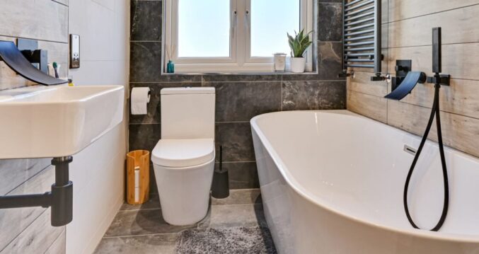 Modern loft bathroom with a freestanding bath, black fittings and timber effect wall tiles in Winchmore Hill N21