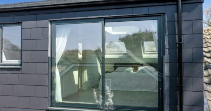 Dark clad rear dormer with a large glazed opening and surrounding pitched roof for the Absolute Lofts Wood Green N22 loft conversion page.