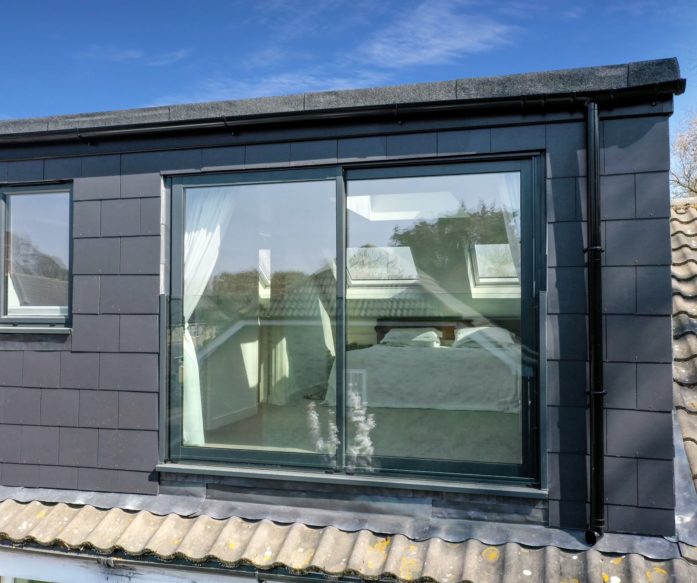 Dark clad rear dormer with a large glazed opening and surrounding pitched roof for the Absolute Lofts Wood Green N22 loft conversion page.