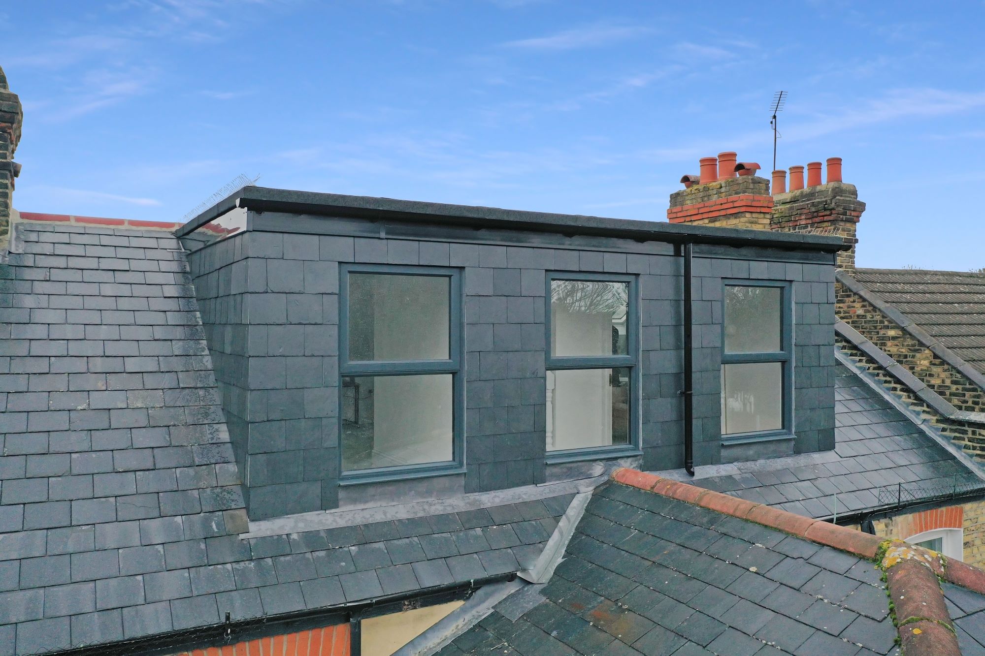 Rear dormer exterior with dark slate cladding, three windows and traditional surrounding roof finishes for the Wood Green N22 loft conversion page.