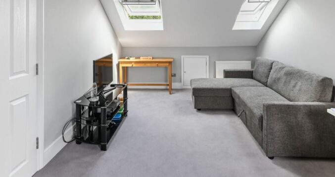 Spacious loft living room with rooflights, grey carpet and a seating area in a Winchmore Hill N21 loft conversion