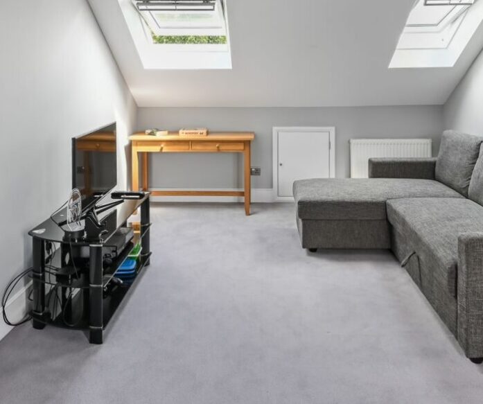 Spacious loft living room with rooflights, grey carpet and a seating area in a Winchmore Hill N21 loft conversion